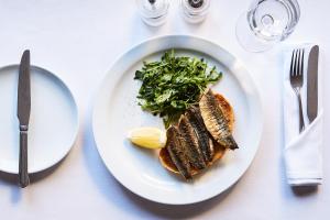 a plate of food with fish and greens on a table at Mercure Newbury West Grange Hotel in Thatcham