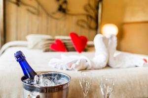 a table with a bottle of champagne and glasses on a bed at Hotel Els Caçadors de Ribes in Ribes de Freser
