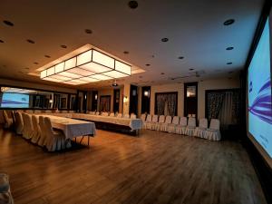 a conference room with tables and chairs and a projection screen at White Park Hotel in Sarıkamıs