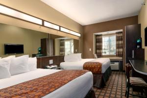 A bed or beds in a room at Microtel Inn & Suites by Wyndham Minot