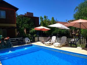 a swimming pool with two umbrellas and two chairs at Complejo ARABELA in Merlo