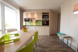 cocina con mesa de madera y sillas verdes en VVF Blériot-Plage, en Blériot-Plage
