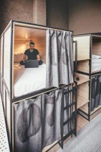 a man sitting in a bunk bed with a laptop at Hide Hostel in Rostov on Don