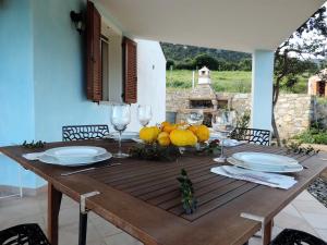 a wooden table with plates and wine glasses on it at la casetta rosa in Tertenìa