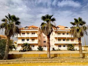 a building with palm trees in front of it at Sal Service Santana double bedrooms sea view angulo in Santa Maria