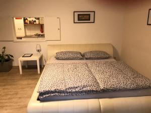 ein Bett mit zwei Kissen und einem Tisch in einem Zimmer in der Unterkunft Studio-Apartment Nähe Erlangen/Herzogenaurach in Großenseebach