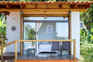 a pergola on a deck with a bed at Haleiwa chalés e suítes - A Guest House do Prumirim in Ubatuba