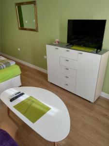 a living room with a tv and a white table at Sasso-студио 3 in Pleven