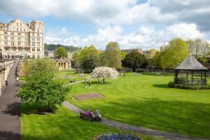 people sitting on a bench in a park with a gazebo at Stunning Spacious Central Apartment near Parade Gardens in Bath