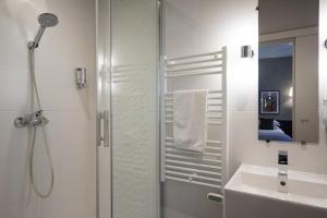 a white bathroom with a shower and a sink at Hotel Voltaire Opera Nantes Centre in Nantes