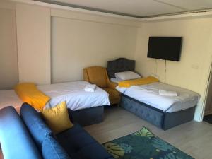 een kamer met 2 bedden, een bank en een flatscreen-tv bij Luxx Suite Mecidiyeköy in Istanbul