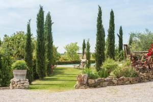 un jardín con cipreses y una pared de piedra. en Agriturismo Pratovalle, en Cortona