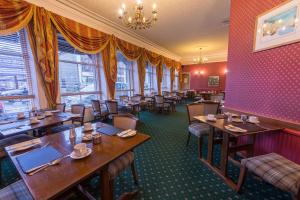 un restaurante con mesas y sillas de madera y ventanas en Pentland Hotel en Thurso