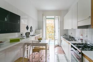 Una cocina con gabinetes blancos y una mesa y sillas. en GREAT HOLIDAY APT accogliente e centrale, en Chiavari