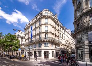 パリにあるHotel Marais Grands Boulevardsの青い看板が立つ高い白い建物