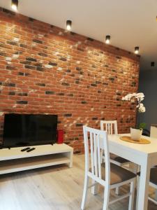 - un salon avec un mur en briques, une table et des chaises dans l'établissement Apartament Centrum Więckowskiego, à Łódź