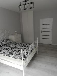 a bedroom with a white bed with a black and white comforter at Apartament Centrum Więckowskiego in Łódź