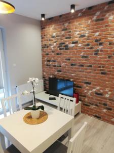 a dining room with a white table and a brick wall at Apartament Centrum Więckowskiego in Łódź