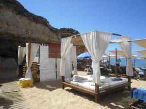 a bed on a sandy beach with umbrellas at Vila Monte Luz in Ferragudo