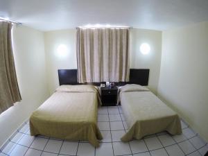 two beds in a small room with a window at Hotel Davimar in Guamúchil
