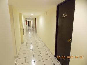 a hallway with a black door and a white tile floor at Hotel Davimar in Guamúchil