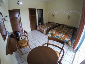 a bedroom with two beds and a table and chairs at Hotel Davimar in Guamúchil