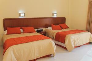two beds in a hotel room with orange pillows at Hotel Davimar in Guamúchil