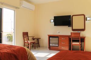1 dormitorio con TV y tocador con espejo en Hotel Davimar, en Guamúchil