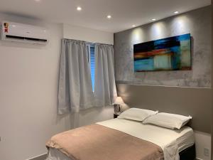 um quarto com uma cama e uma pintura na parede em The Best Apartment in Copacabana - Quarto e Sala no Rio de Janeiro