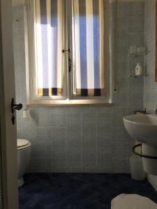 Appartamento Acquamarina في مارينا دي سيسينا: حمام مع حوض ومرحاض ونافذة
