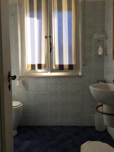 a bathroom with a sink and a toilet and a window at Appartamento Acquamarina in Marina di Cecina
