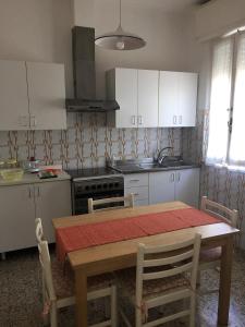 a kitchen with a wooden table and a kitchen with white cabinets at Appartamento Acquamarina in Marina di Cecina