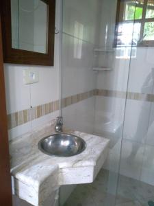 a bathroom with a sink and a glass shower at Casa dos Coqueiros Praia de Camburi, condomínio in Camburi