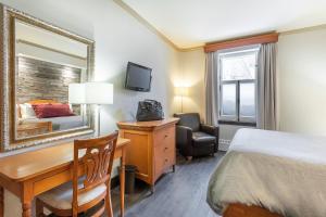 a hotel room with a bed and a desk and a mirror at Hotel Chateau Bellevue in Quebec City