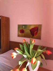 a vase of flowers sitting on a bed with a painting at Hotel Haga in Częstochowa