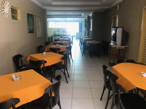 a dining room with tables and chairs and a television at Hotel Santos Reis in Trindade