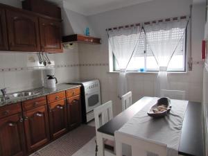 a kitchen with wooden cabinets and a table with a bowl on it at Zambeachouse - Beach & Country in Lourinhã