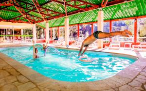 um cachorro pulando em uma piscina com um frisbee em Hotel Fazenda Floresta Negra em Monte Verde