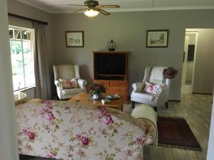 uma sala de estar com um sofá e cadeiras e uma televisão em Idavold Cottages em Howick
