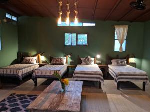 a room with three beds and a table in it at Bohemyan Blue Stay in Alibaug