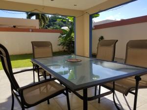 une table et des chaises en verre sur la terrasse dans l'établissement Tropical Delightful Guest Studio, à Canovanas
