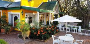 Casa amarilla con mesa y sombrilla en Hosteria El Colonial en Baradero