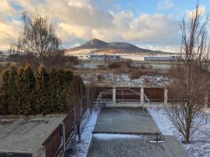 ein schneebedecktes Feld mit einem Zaun und einem Berg in der Unterkunft Motel Red Oil in Lovosice