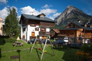 a playground in front of a house with a mountain at Appartamenti Anna Benedetti in Sappada