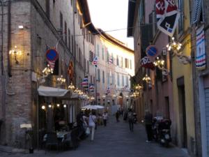an alley with people walking down a street with buildings at La casa in Camollia in Siena