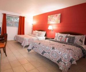 1 dormitorio con 2 camas y pared roja en Gables Inn en Miami