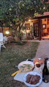 una mesa con platos de comida y una botella de vino en Czarina Cabin הבקתה הקיסרית, en Cesarea