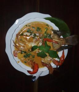 a plate of food with a fish in a sauce at Casa Maya in Lívingston