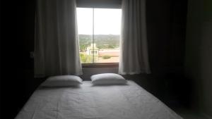 a bed with two pillows in a room with a window at Topázio Park Hotel in Afrânio