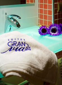 a towel sitting on a bathroom sink with purple flowers at Suites Gran Vía 44 in Granada